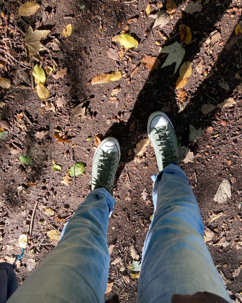 Grüne Sneaker auf einem Waldweg mit herbstlichem Laub